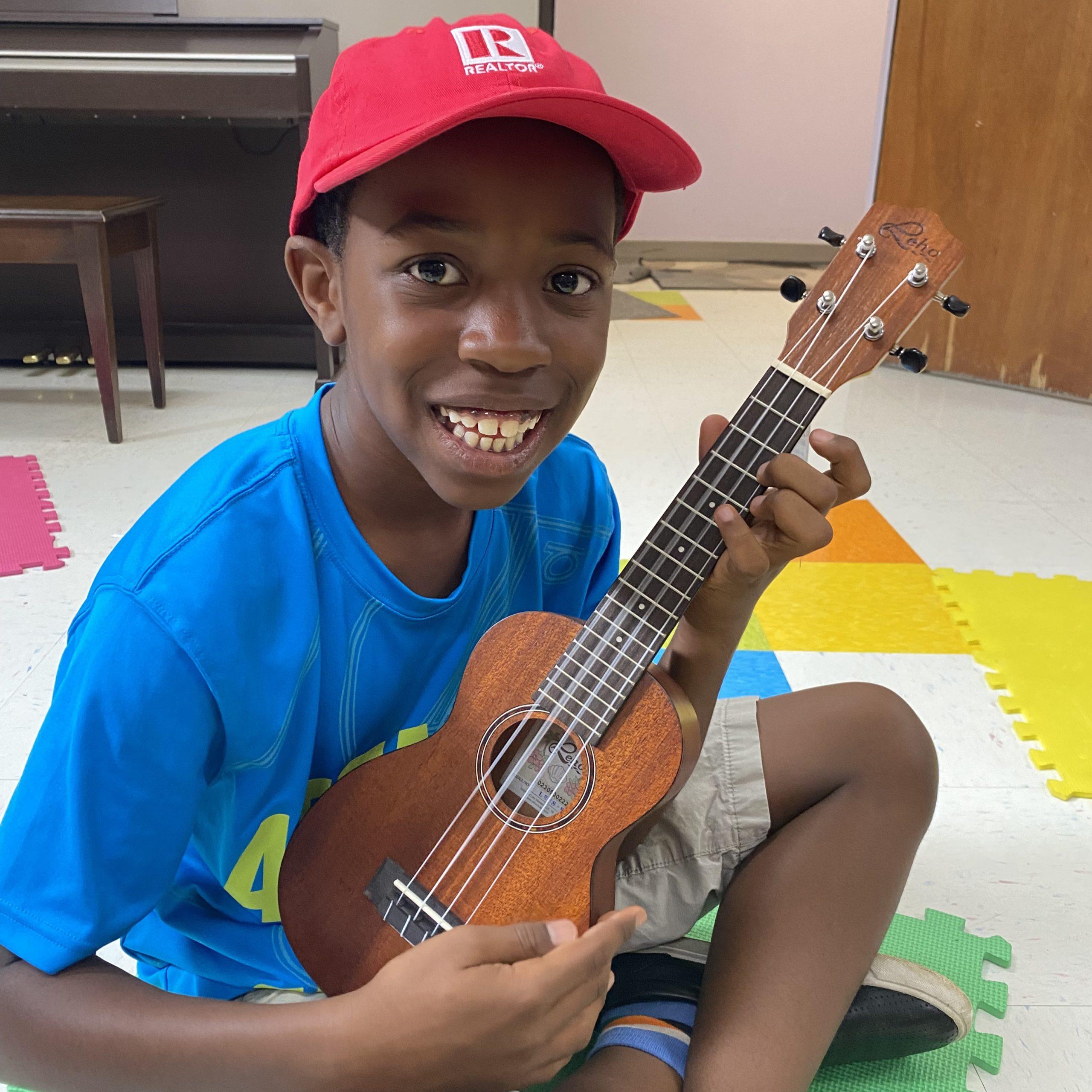 Smiling kid sitting with a ukulele.